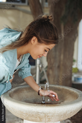Woman drinking water from fountain. Young Woman drinking from a fresh water drink fountain