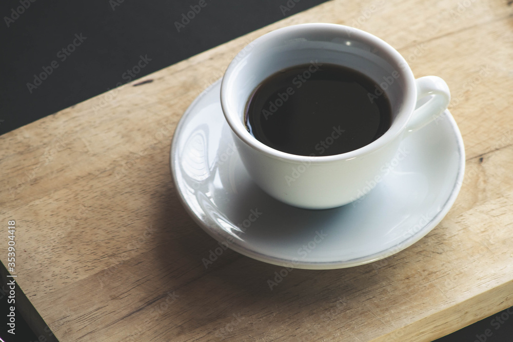Black coffee in a white mug with a saucer placed on a wooden plate and served in the morning. Black coffee in a white mug with a saucer placed on a wooden plate and served in the morning.
