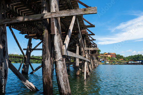Mon wooden bridge above songaria river Sangkhla Buri District, Kanchanaburi, Thailand. photograph by ant view by boat trip against blue sky. travel after covid-19 lockdown.