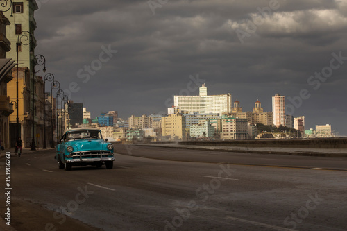 Fototapeta Naklejka Na Ścianę i Meble -  Old car on Malecon street of Havana with storm clouds in background. Cuba
