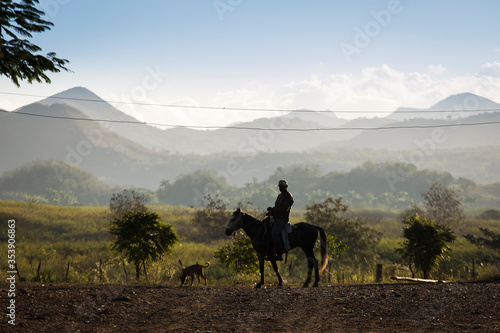 Silhouette of country man on horses with beautiful mountains in background in Vinales  Cuba