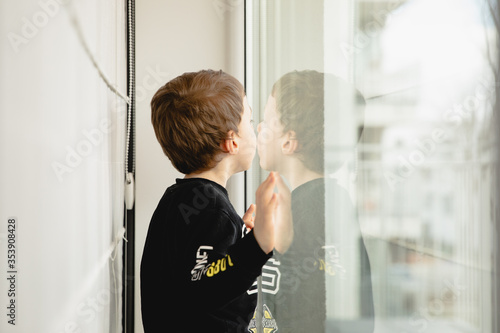 Obraz na płótnie little boy looking through the window inside the house 