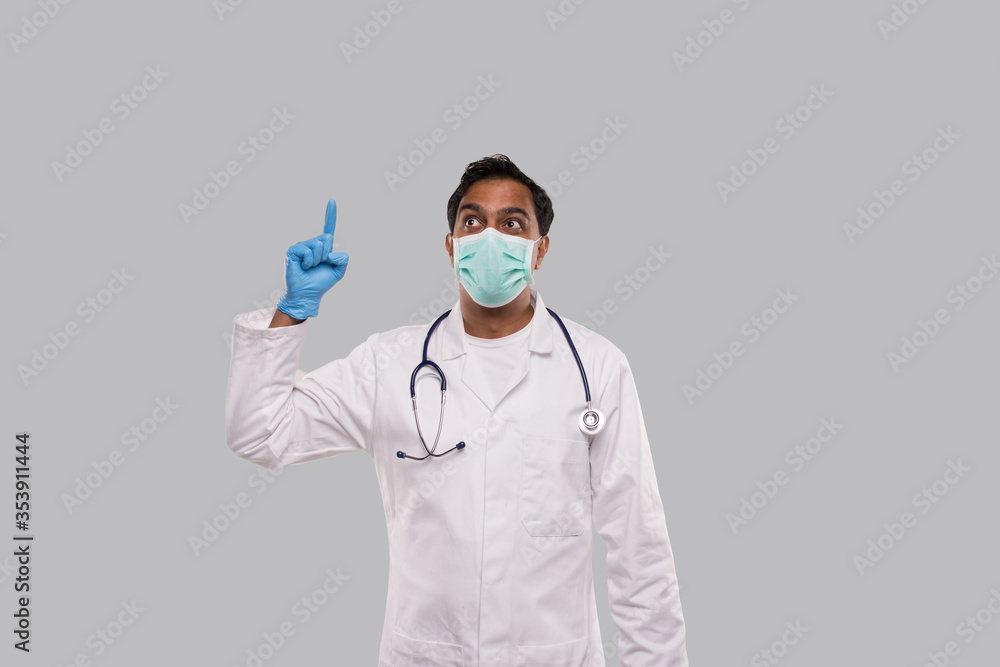 Indian Man Doctor Pointing Up and Watching Up Wearing Medical Mask and Gloves Isolated Indian Man Doctor Pointing Up and Watching Up Wearing Medical Mask and Gloves Isolated