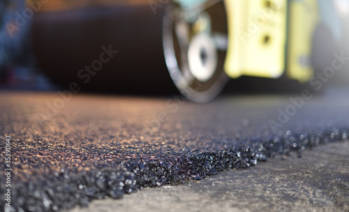 Road repair, thin layer of new asphalt close-up and road roller