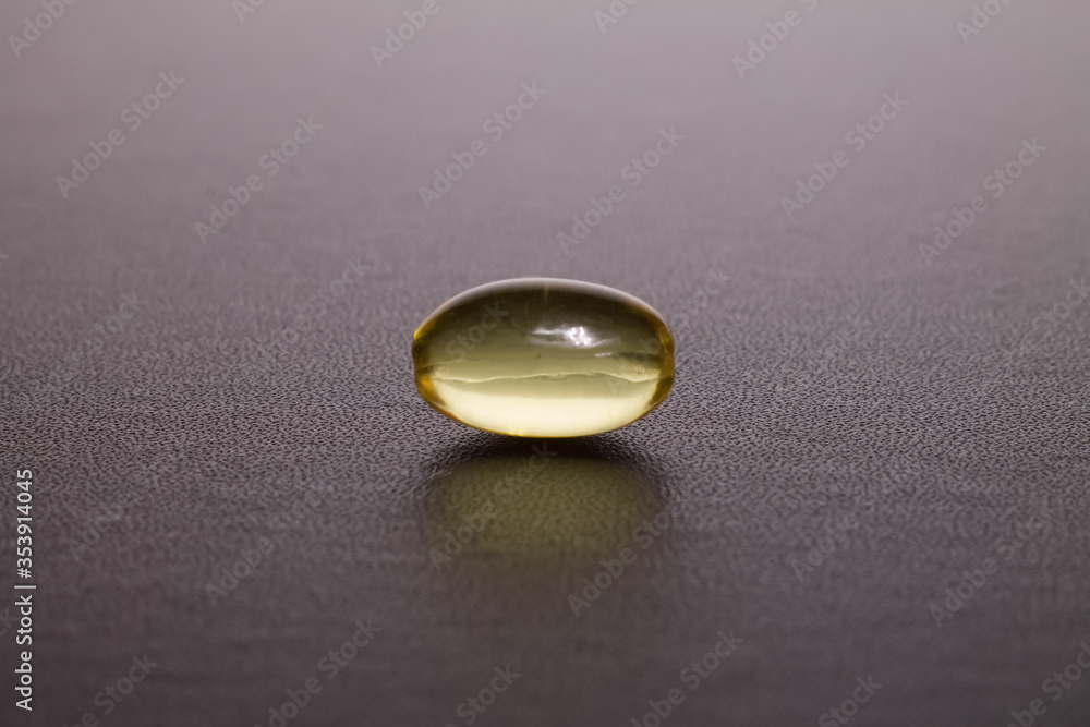 yellow translucent capsule lies on a dark background yellow translucent capsule lies on a dark background