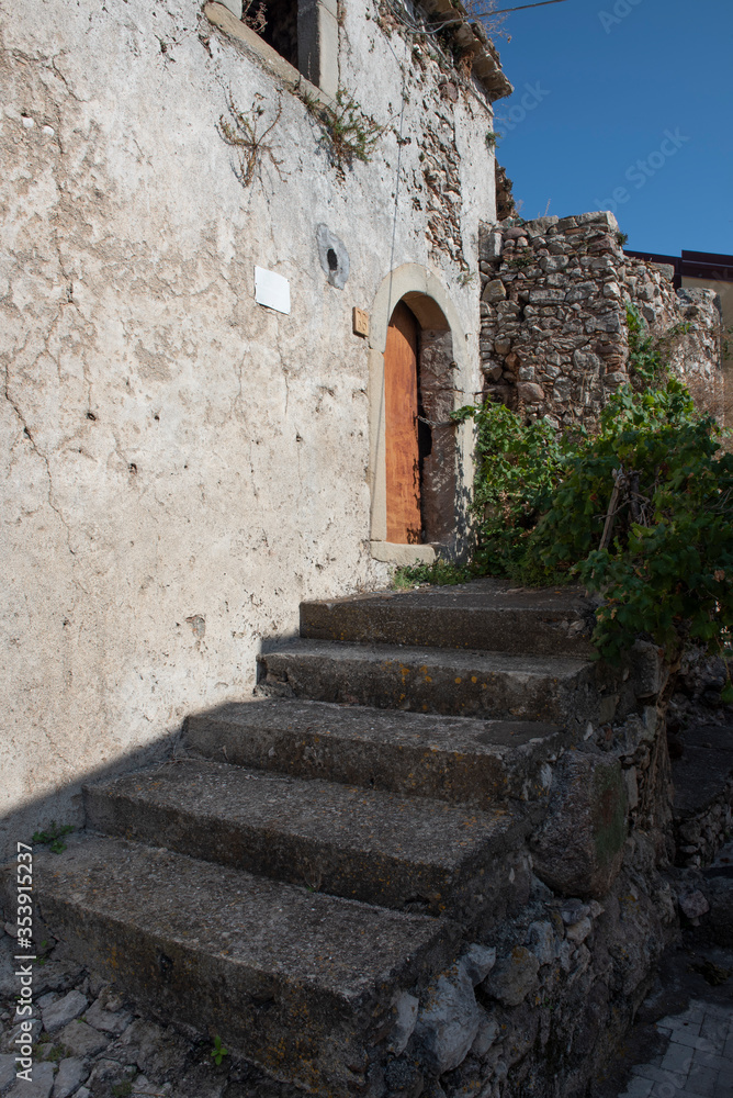 A shaded, old, stone-clad concrete staircase following the path through an Italian village on a sunny day