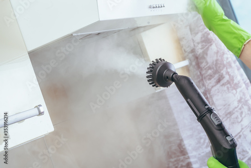 cleaning in the house. The girl cleans the steam generator with a light kitchen surface, extract. High pressure wet steam cleaning. we kill microbes photo