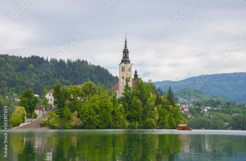 Beautiful morning at Lake Bled and Julian Alps in the background. The lake island and charming little church dedicated to the Assumption of Mary are famous tourist attraction in Slovenia