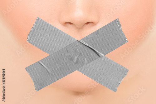 Woman silenced with adhesive duct tape covering closed mouth. Censorship, shut down of freedom of speech. Face nose and lips. photo