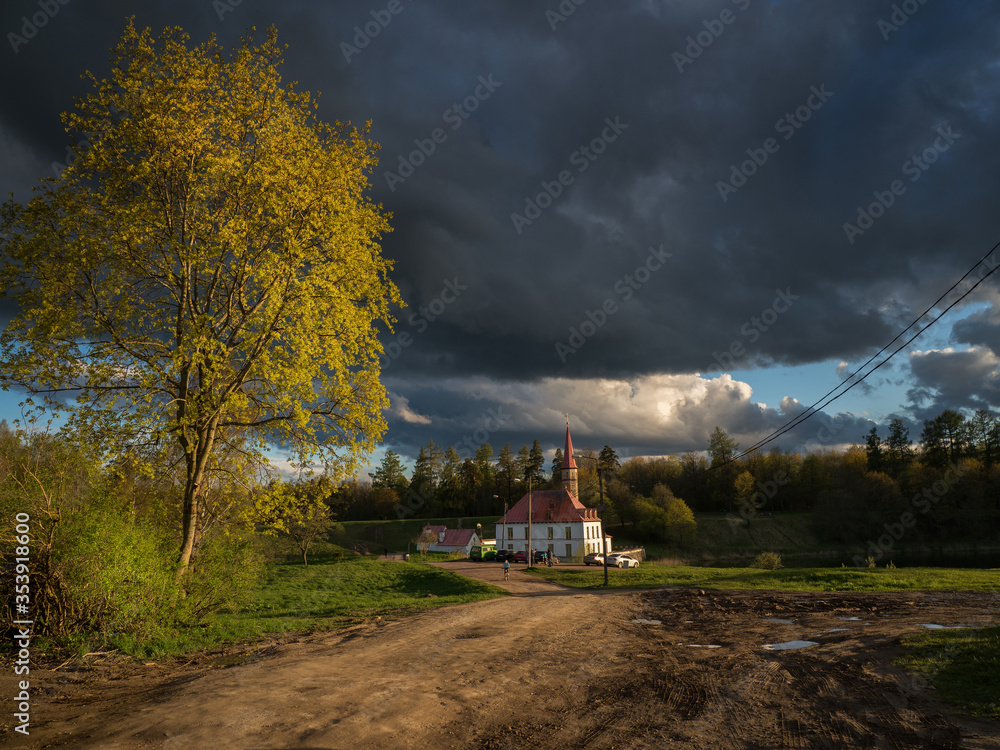 Obraz premium Evening countryside landscape with dramatic rain clouds and the road to the ancient palace