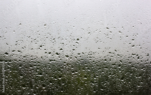 Raindrops on the window pane outside the window you can see the green forest and gray sky