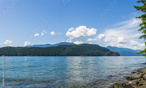 veiw from the shore to Harrison Lake british columbia Canada green land blue water and sky.