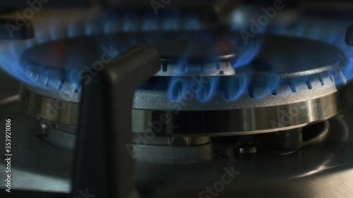 The gas is ignited by a blue flame in the kitchen on a large wok burner. Taken in motion close-up. #3