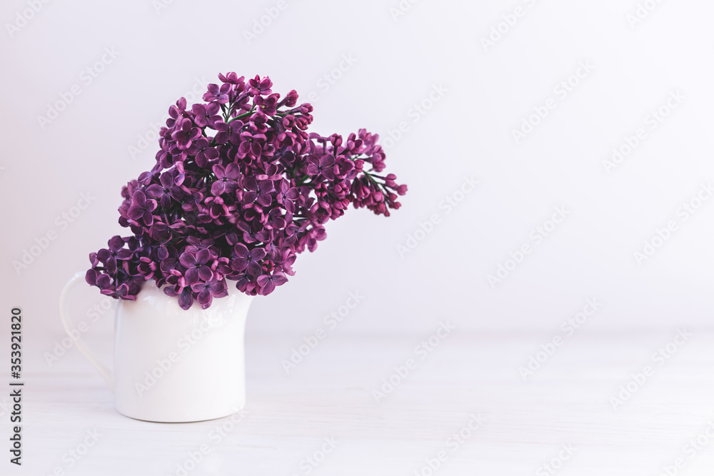 Fototapeta premium Romantic bouquet of a dark purple lilac in a jar on a white background.