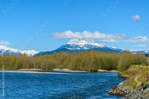 Majestic mountain river in winter over snow mountains and blue sky in Vancouver, Canada.