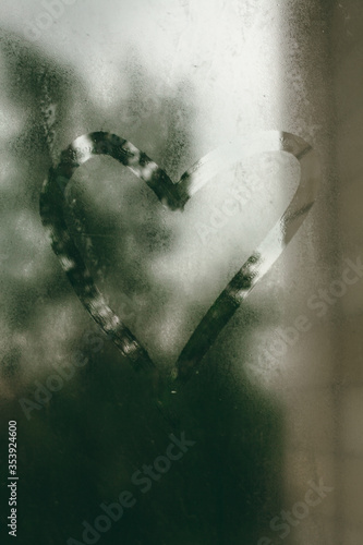 Painted heart on a foggy window. Cloudy and rainy weather.
