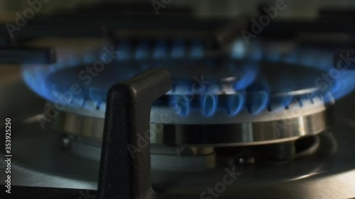 Gas is burning in the kitchen on a wok burner. Shot in motion, smoothly moving away.