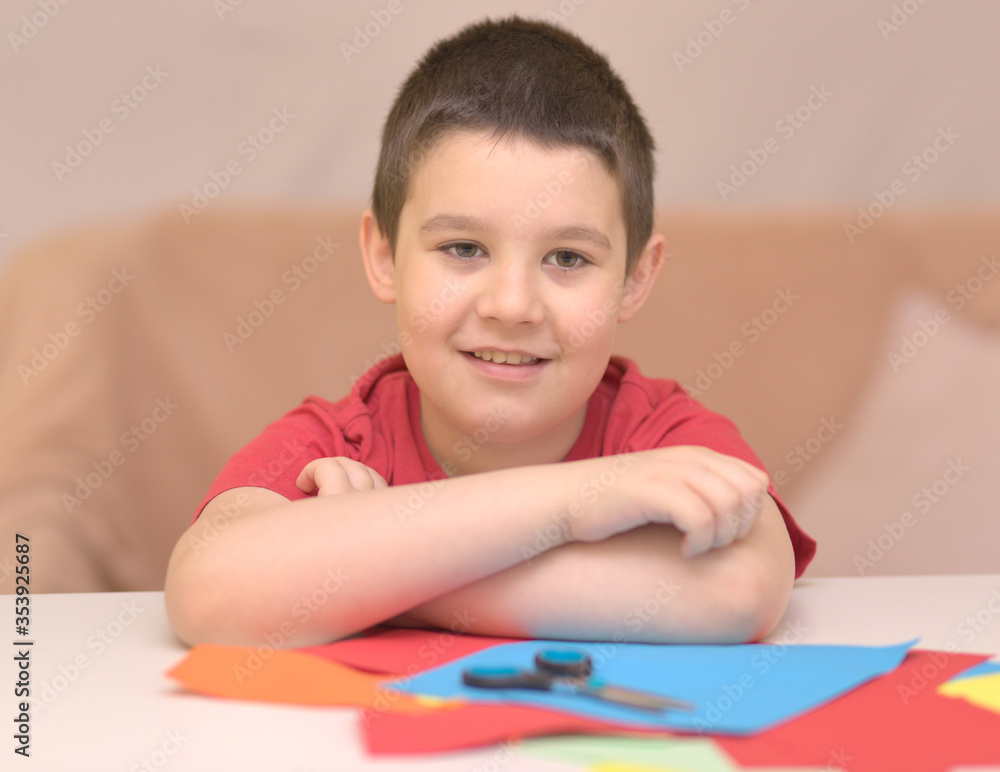 Cute smiling boy is cutting paper using scissors. Education, school concept Cute smiling boy is cutting paper using scissors. Education, school concept