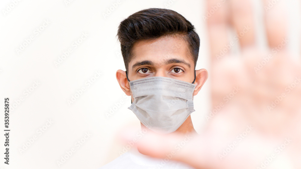 Young Asian boy wearing protective mask against the corona virus covid 19 and stopping people to interact with each other brown man with surgical mask to prevent from virus white background blur hand Young Asian boy wearing protective mask against the corona virus covid 19 and stopping people to interact with each other brown man with surgical mask to prevent from virus white background blur hand