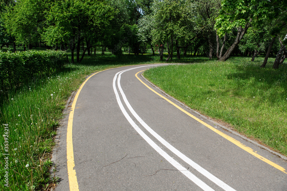 Obraz premium Turn of bike path in spring park. Empty road.