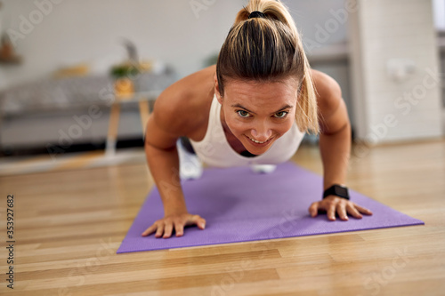 Young sportswoman doing push-ups while exercising a t home.