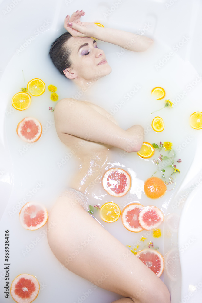 Obraz premium An attractive girl takes a bath with milk and flowers. Spa treatments for skin rejuvenation
