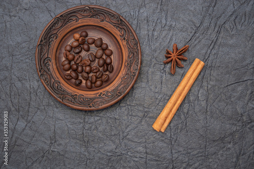Homemade saucer made of glazed clay. A pinch of brown roasted aromatic coffee beans.