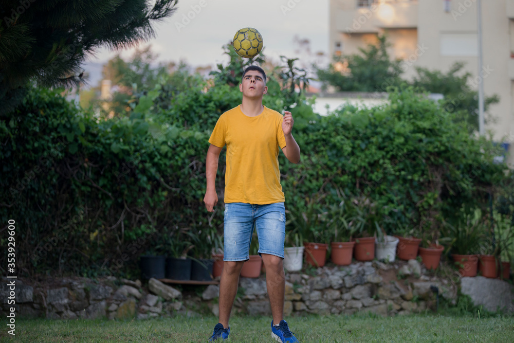 Teenager in playing football in a garden. Teenager in playing football in a garden.