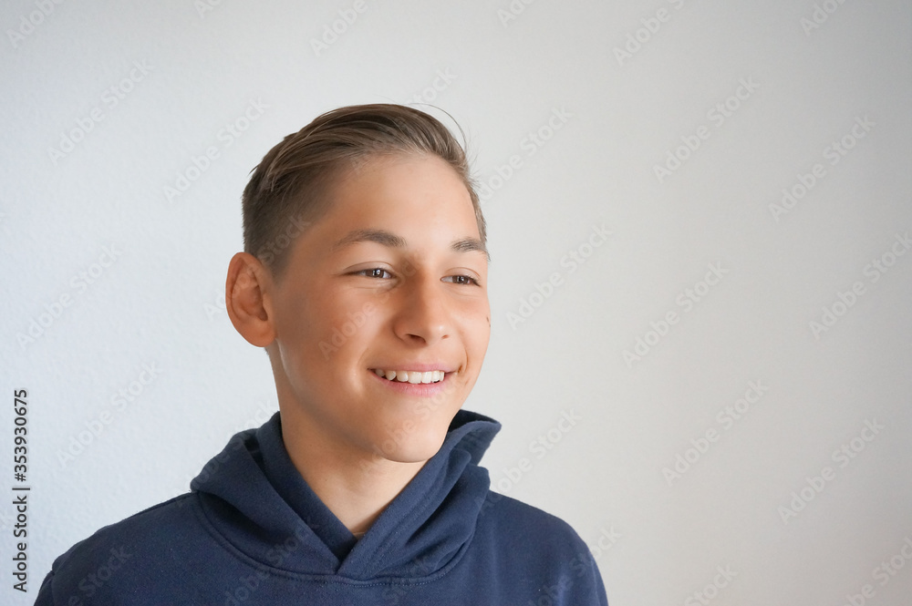 Young happy smiling teenager guy looking aside on grey background Young happy smiling teenager guy looking aside on grey background