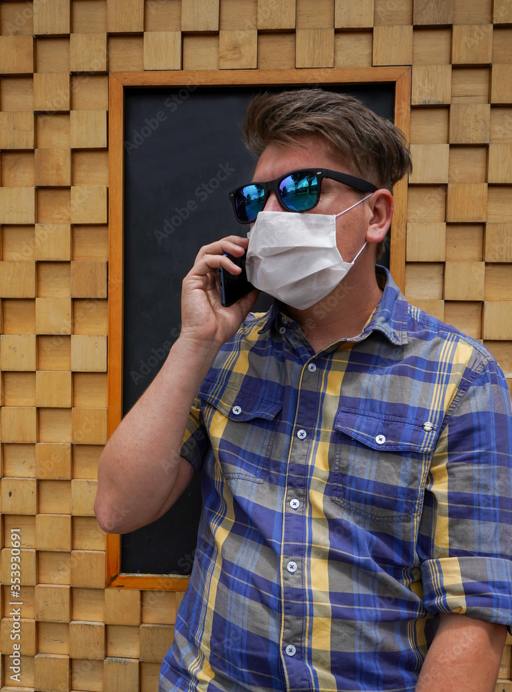 White man in blue plaid shirt making a call on his cell phone wearing face  mask Photos | Adobe Stock