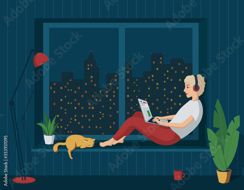 Young happy girl in home clothes is sitting at the window with a laptop in headphones. Night city outside the window. Remote work from home. Freelance. Learning on the Internet. Online Store Shopping