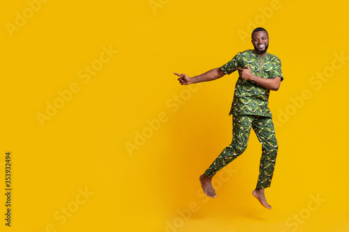 Excited black guy jumping and pointing at free space