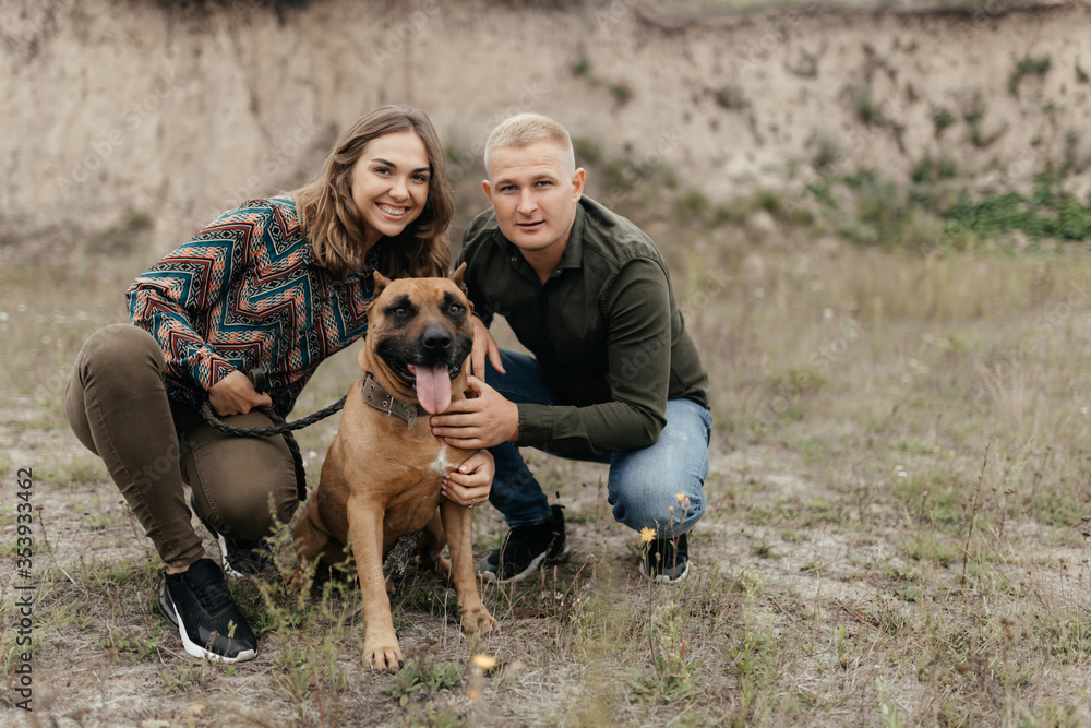Smiling man and woman sitting near their dog in nature Smiling man and woman sitting near their dog in nature