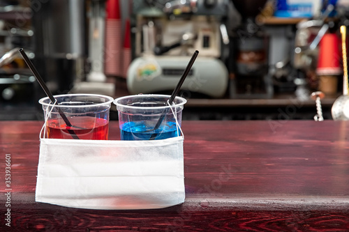 two plastic cups and a medical mask on the bar