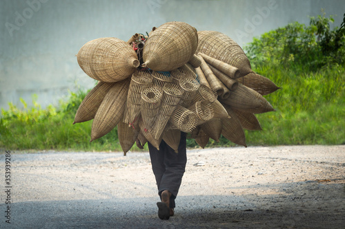 Old men are walking for selling wicker craftsman making traditional bamboo fish trap or weave in Hanoi, Vietnam