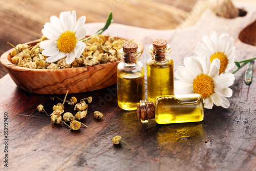 Chamomile Composition with essential oil and chamomile flowers on wooden rustic table