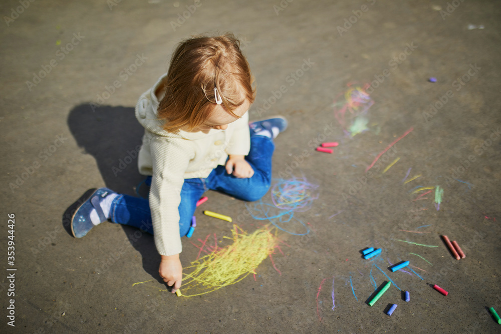 Naklejka premium Adorable toddler girl drawing with colorful chalks