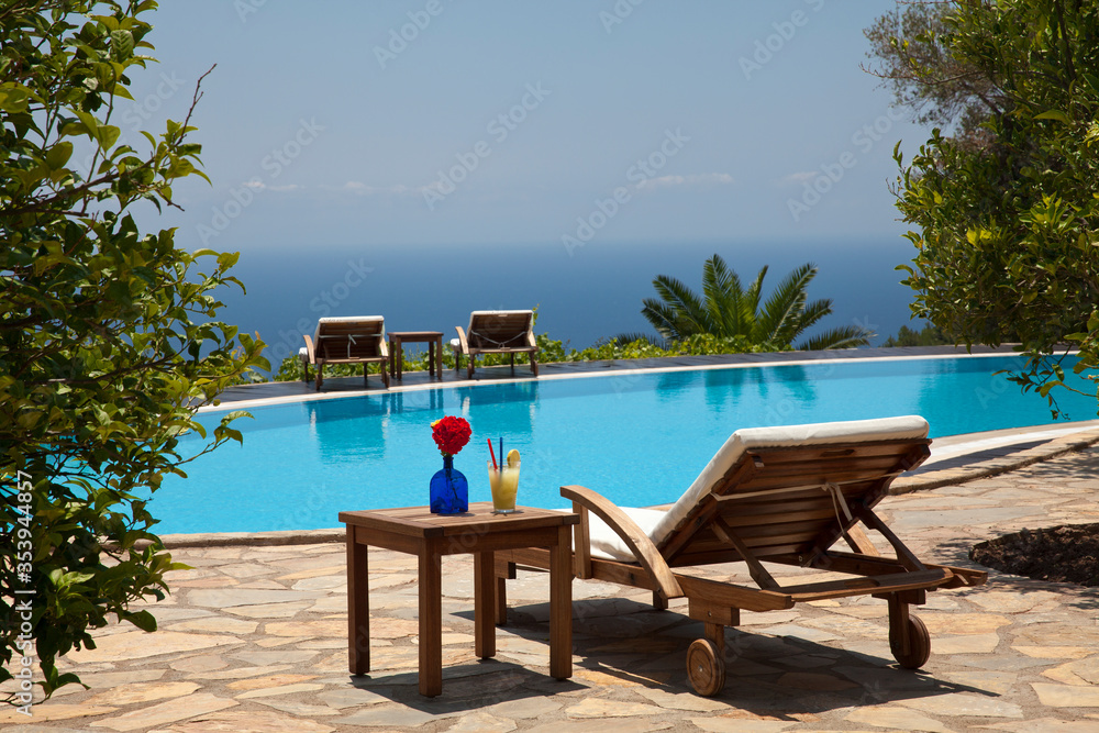 Fresh summer drink and sunbed. Swimming pool with a beautiful sea background.