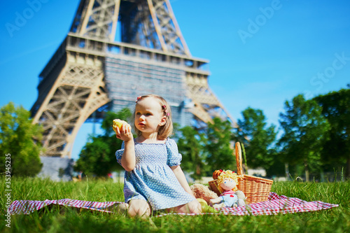 Cheerful toddler girl having picnic near the Eiffel tower in Paris photo