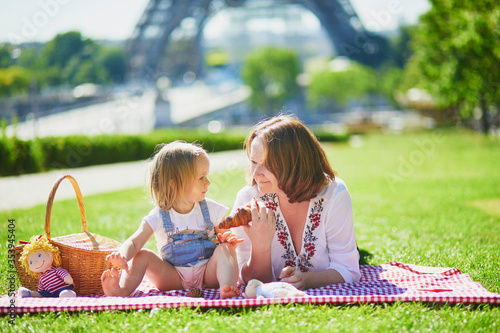 Young woman with toddler girl having picnic near the Eiffel tower in Paris photo