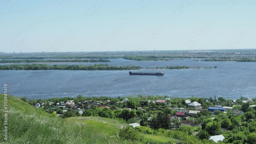 A beautiful landscape with a view of a wide river on which a barge sails and on the Bank there is a village A beautiful landscape with a view of a wide river on which a barge sails and on the Bank there is a village