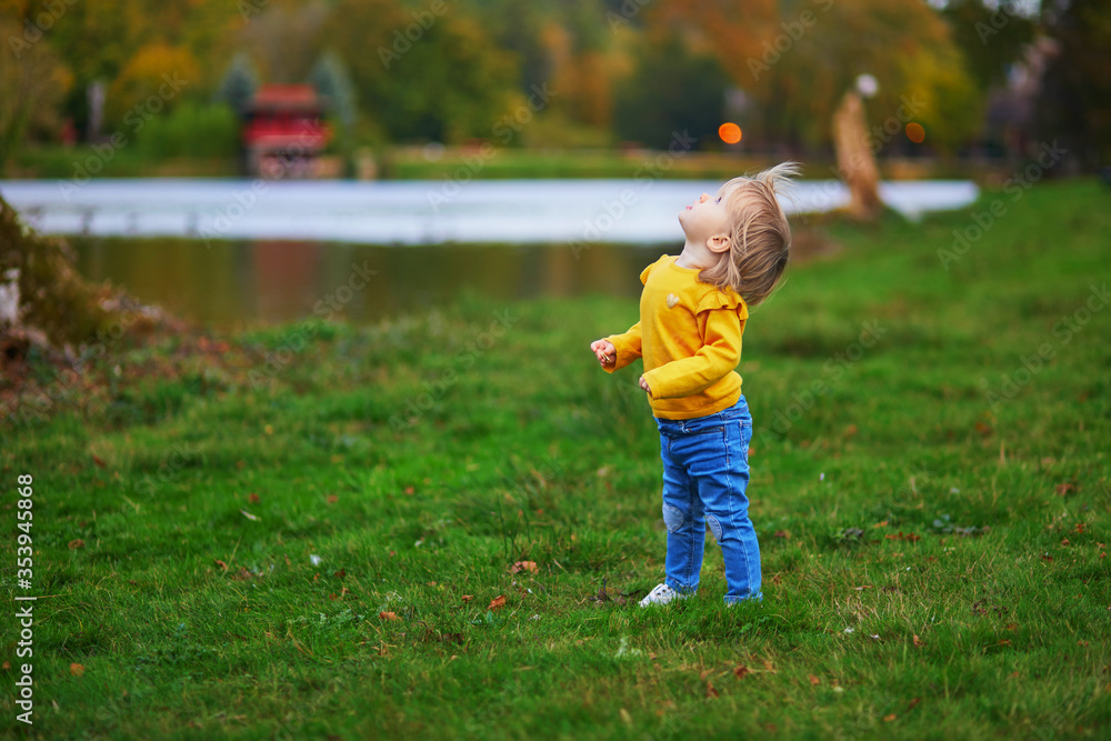Adorable cheerful toddler girl running in autumn park in Paris Adorable cheerful toddler girl running in autumn park in Paris