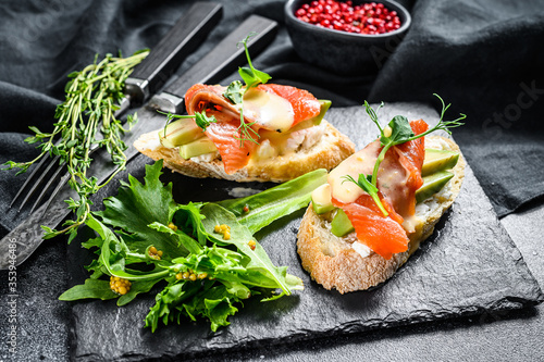 Toasts with avocado and smoked salmon.  Black background. Top view