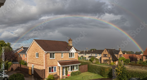 rainbow arcs over a house on a stormy day in spring in the UK second rainbow can be seen