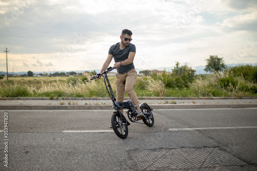 Caucasian attractive man rides his e - bike on the street to go to work and in his leisure. Electric bibycle concept. Ecologic mobility concept. Modern transportation. Electric biking . Cycling man 