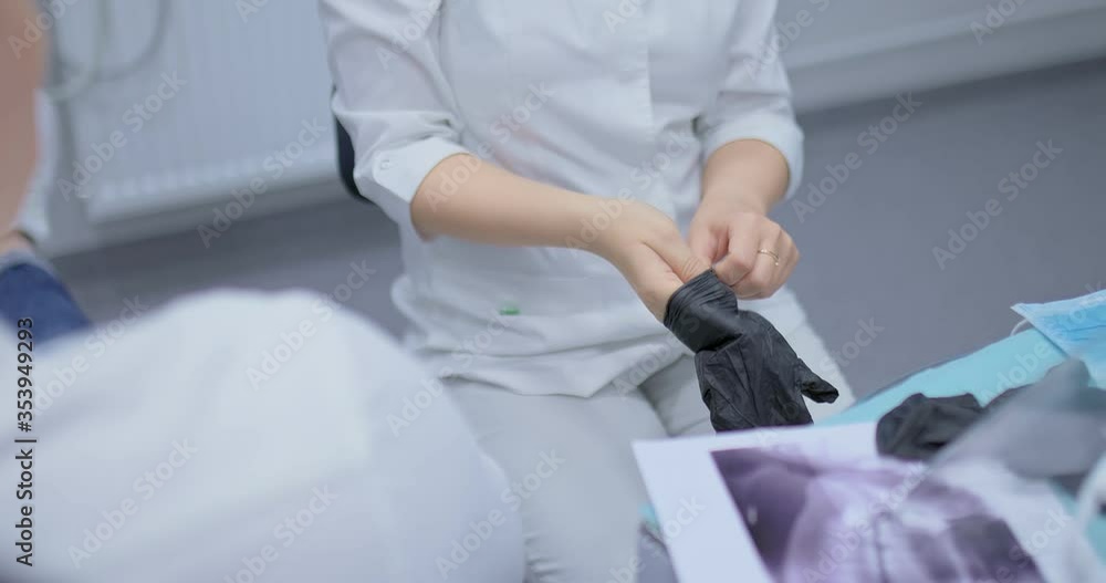 Doctor puts on black sterile gloves, the beginning of treatment. Professional medical uniform. Close-up.