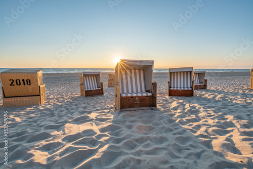 Fototapeta Naklejka Na Ścianę i Meble -  Roofed wicker beach chairs at the North Sea coast on Sylt, Germany	