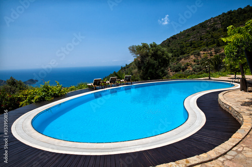 Swimming pool in the garden and beautiful sea and mountain landscape with trees.