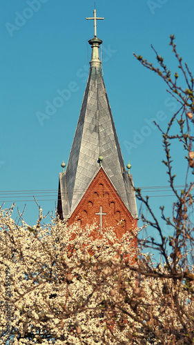 Kościelna wieża wyłaniająca się z kwitnących drzew owocowych