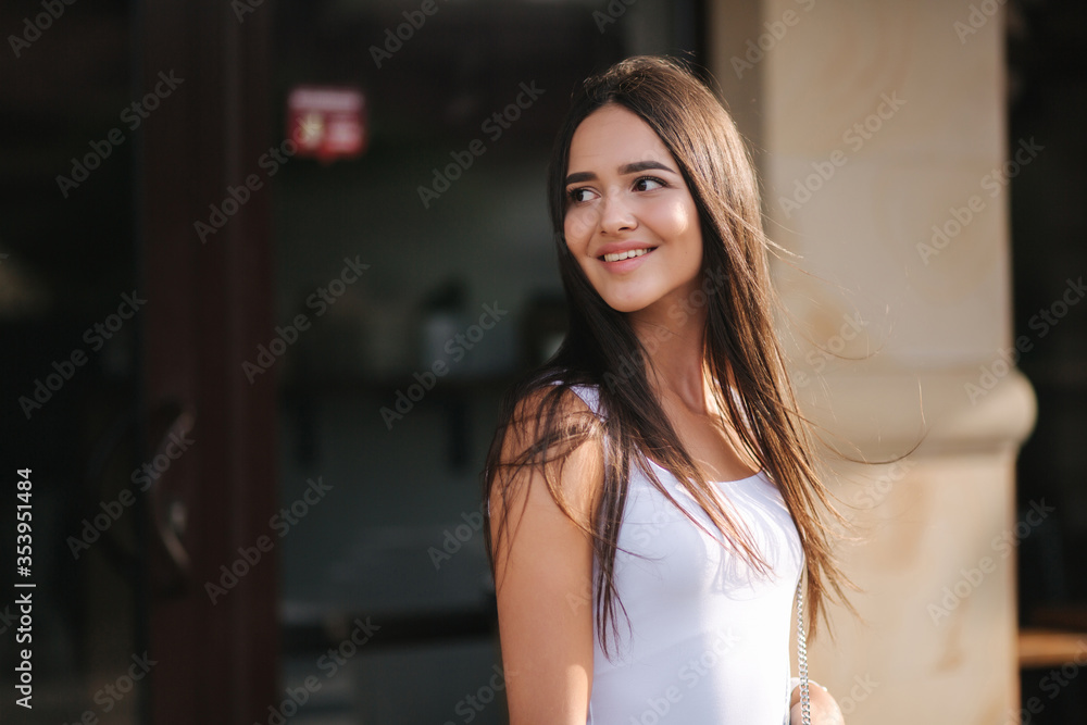 Portrait of young woman standing by the cafe. Woman wait for shop coffee. Happy smiled woman after quarantine